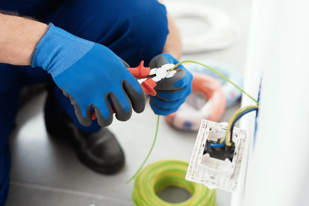 Électricien utilisant une pince coupante pour couper un fil électrique