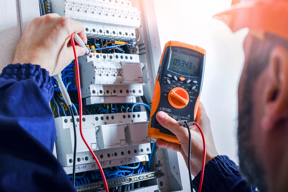 Électricien vérifiant les mesures sur un panneau électrique avec un multimètre