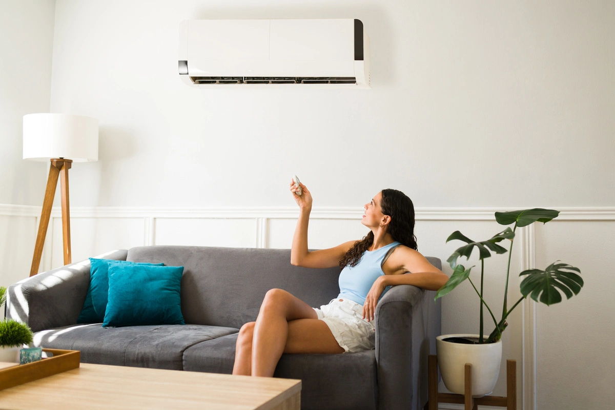 Femme utilisant une télécommande pour régler la climatisation