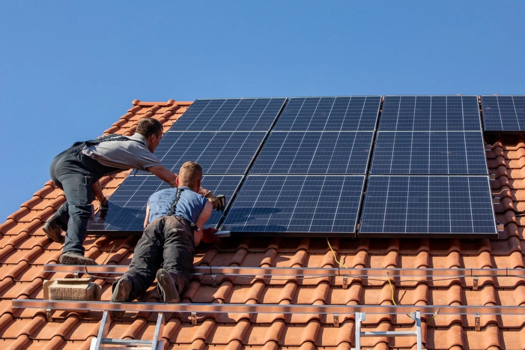 Installation de panneaux photovoltaïques par des professionnels sur un toit incliné en tuiles rouges