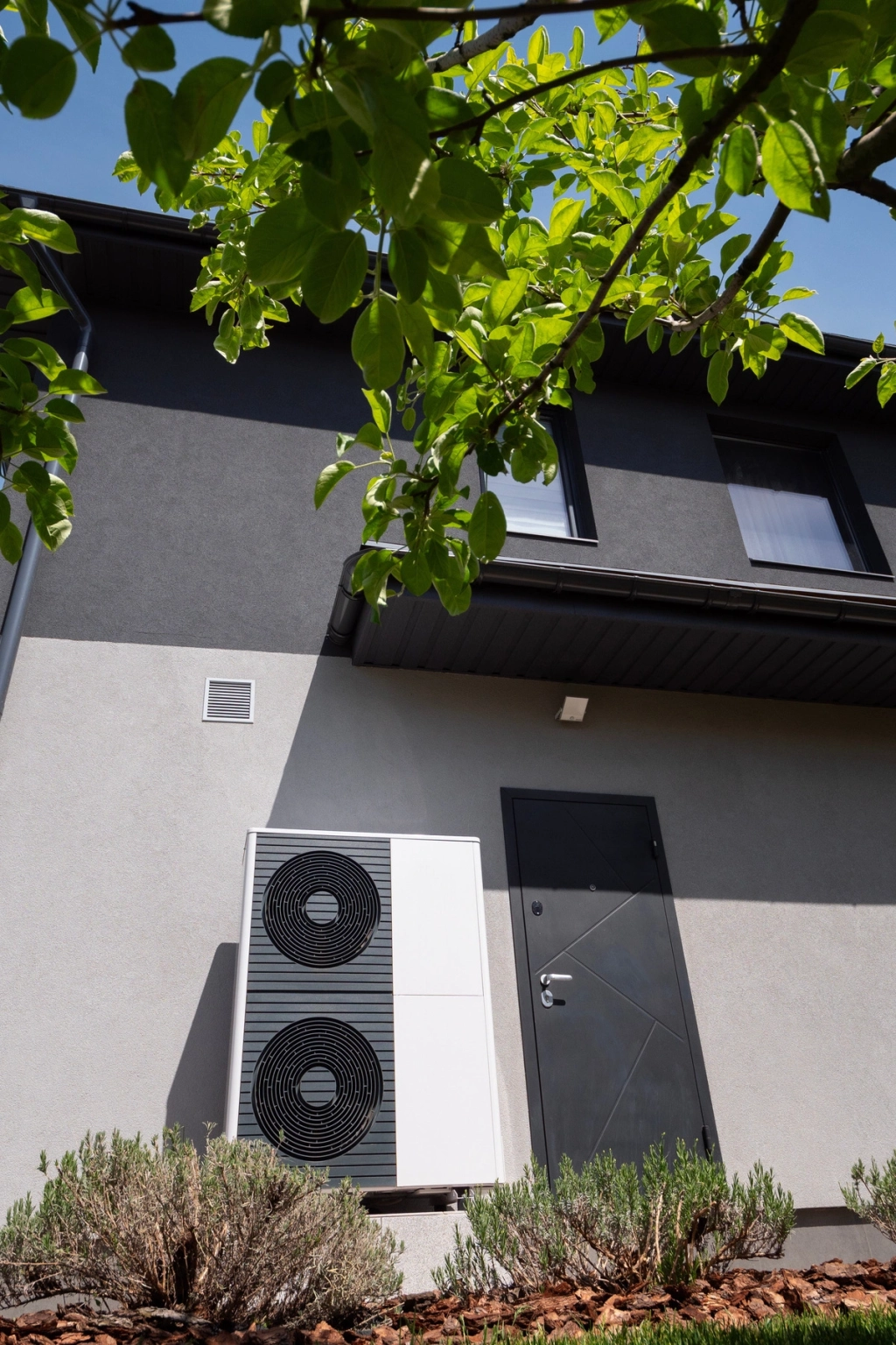 Unité extérieure de pompe à chaleur installée sur le mur d'une maison moderne.